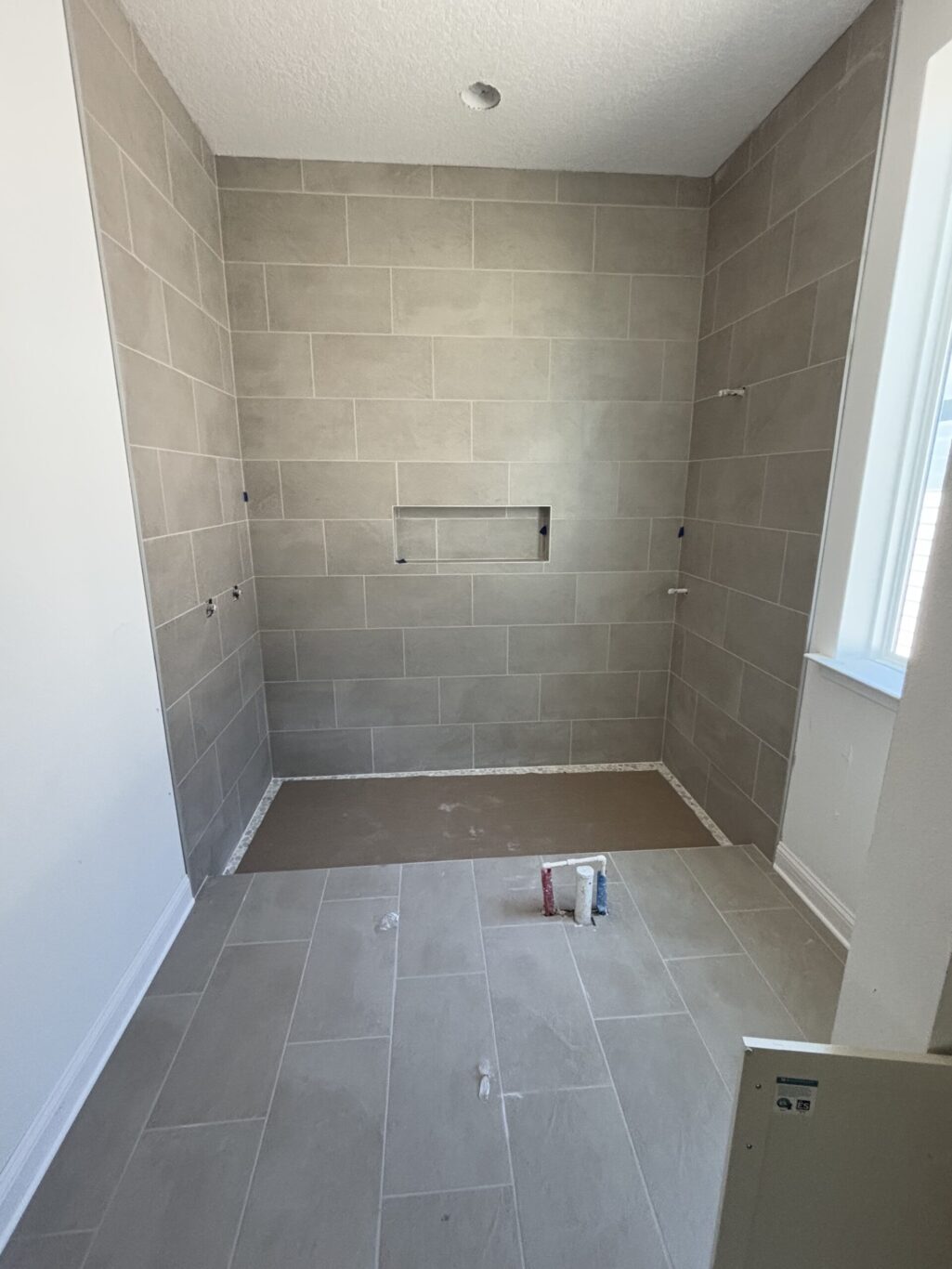 "A waterproof PVC shower liner installed with corner folds and a three piece drain assembly for a bathroom remodel"